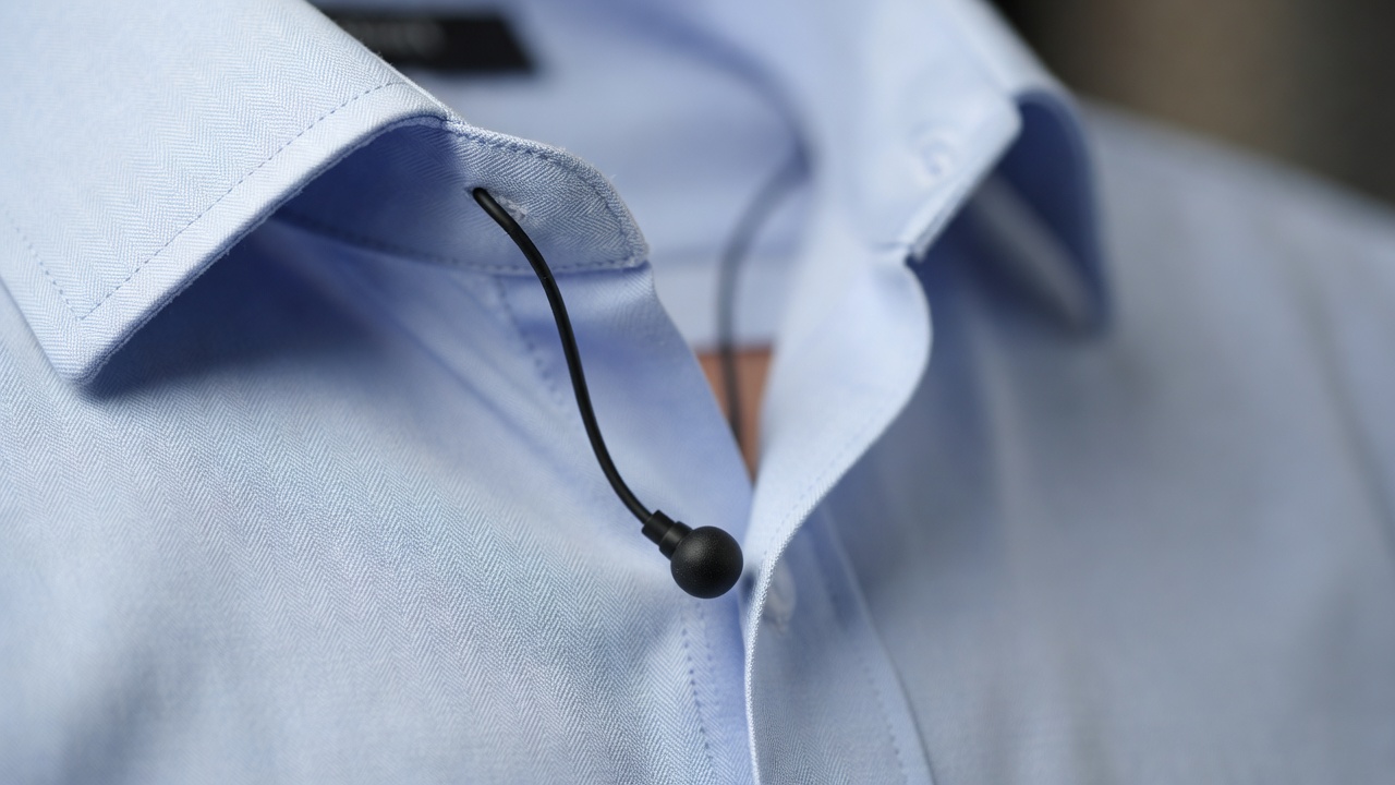 Shallow-focus close-up of a lavalier microphone hidden at a shirt placket