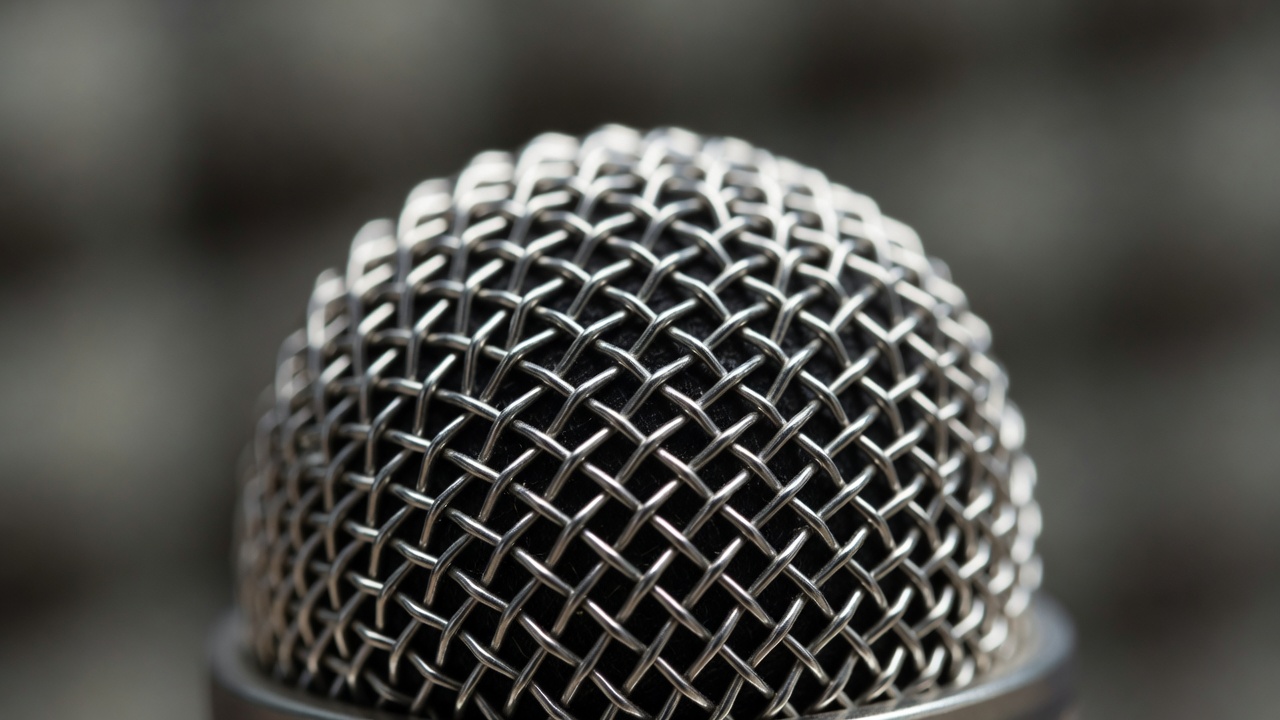 Extreme close-up of a studio microphone's metal mesh grille with shallow focus